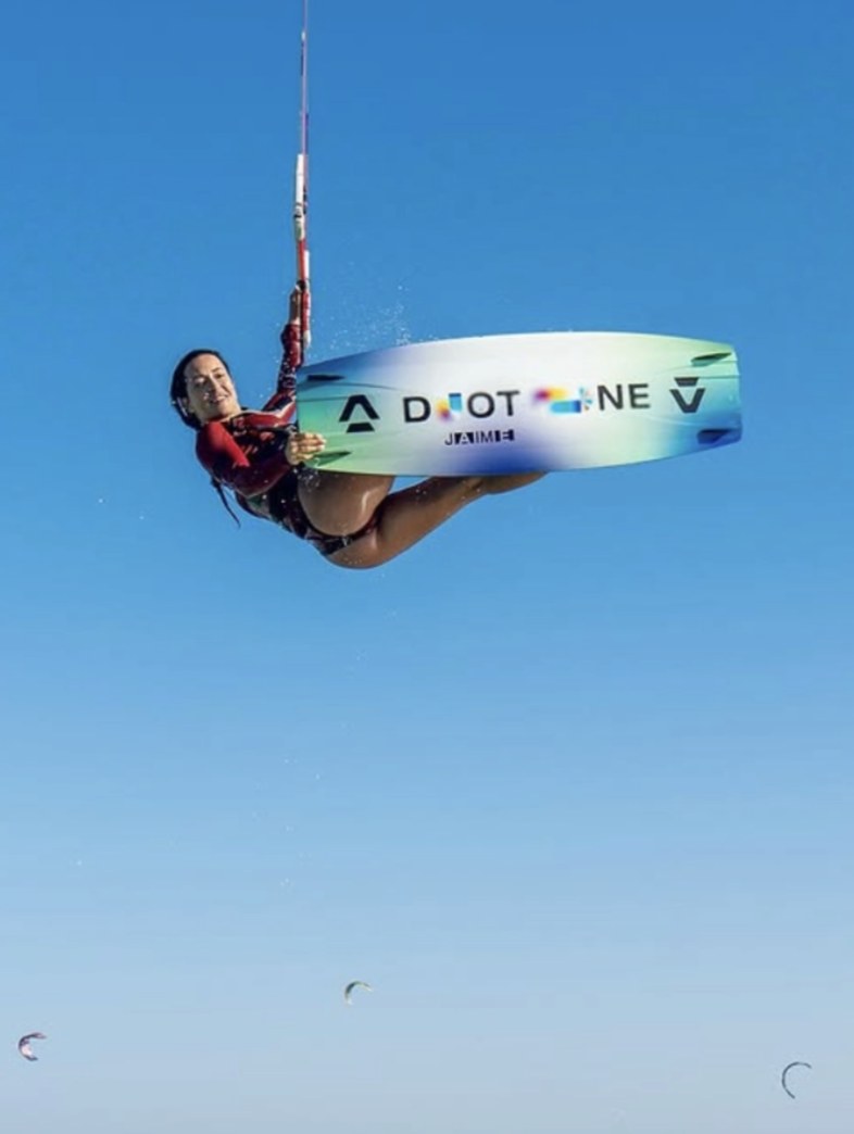 Kitesurfer grabbing the board mid-air against a deep blue sky