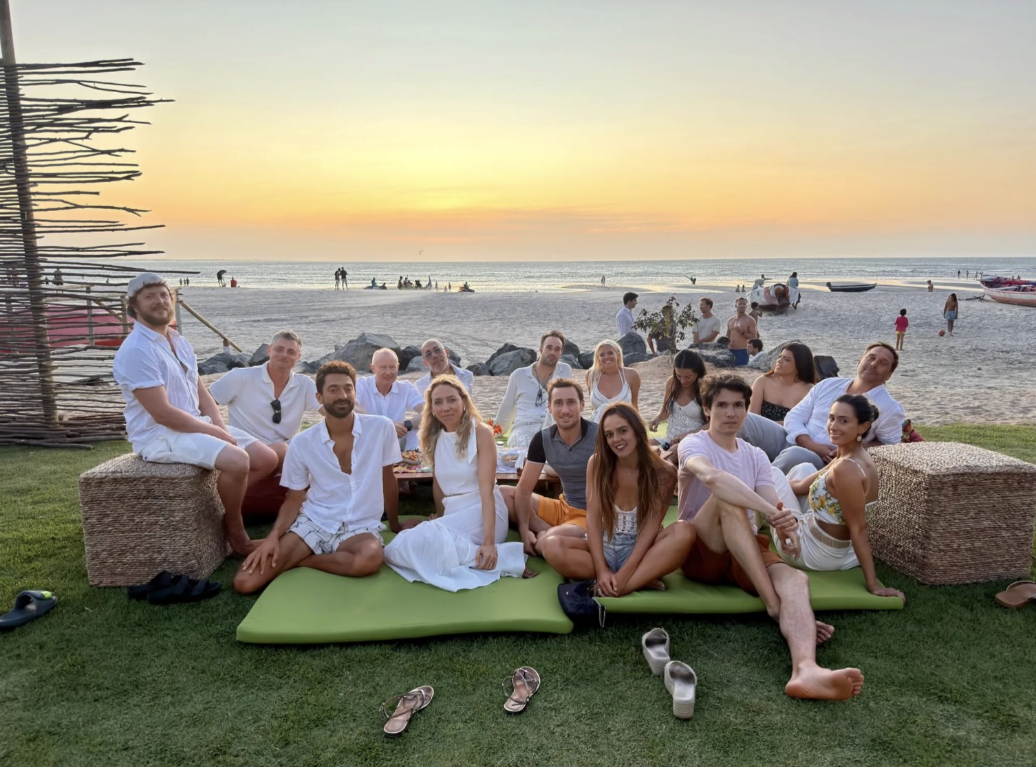 The whole crew in white on cushions at a beach sunset party